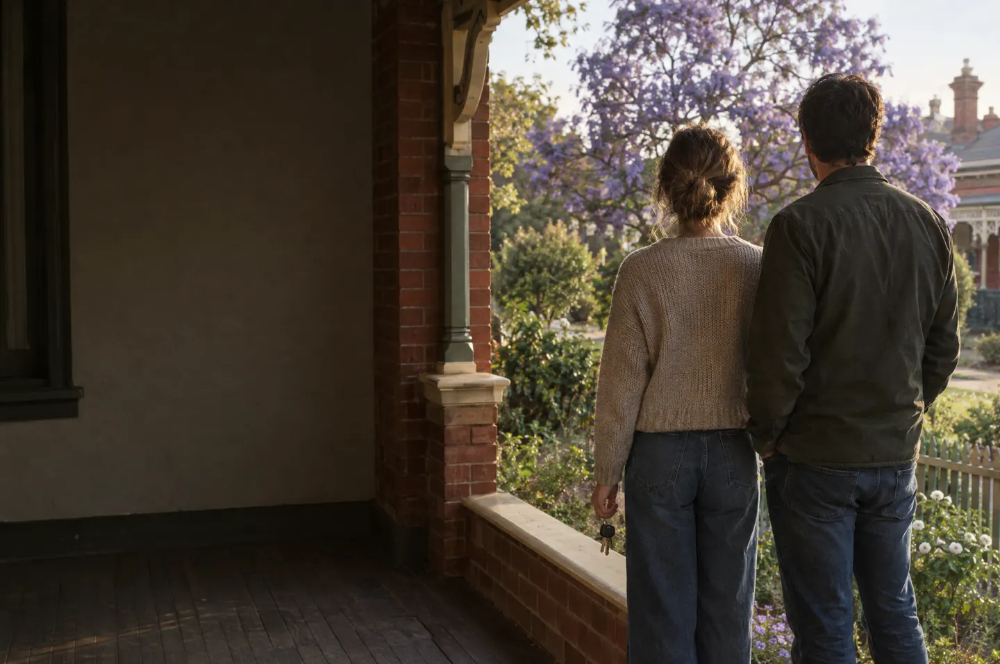 A couple on the verandah of a brick house, keys in hand. Placeholder.