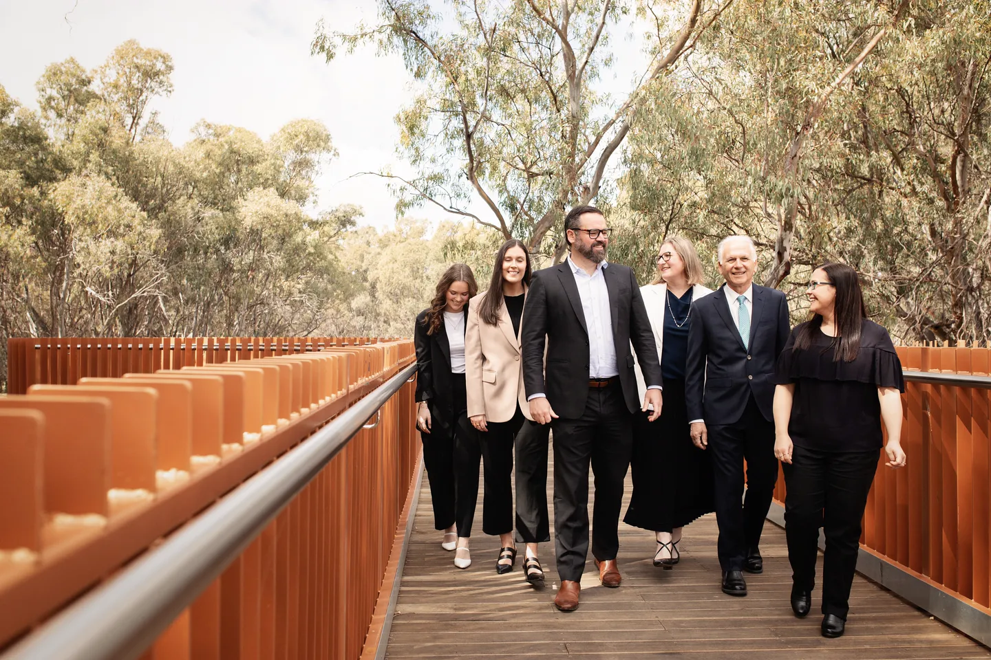 Six members of the property team walking along a timber boardwalk among river red gums.