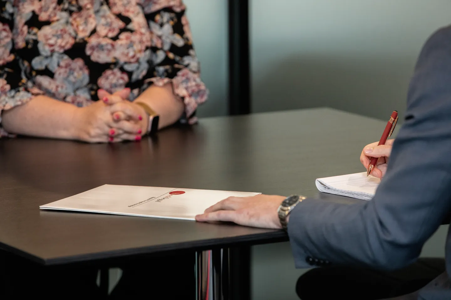 Hands with a red pen beside a Beck Legal folder on a meeting table